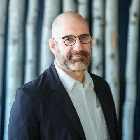 Caucasian man with beard, glasses, dark jacket and white collared shirt